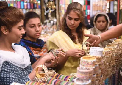  ?? AFP ?? Women buy bangles at a shop ahead of eid Al Fitr in Karachi. the festive occasion, which marks the end of the holy month of ramadan, is likely to be observed on Friday in Pakistan. —