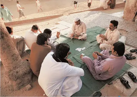  ?? AMRNABIL/AP ?? Workers play cards while on holiday in January in Jiddah, Saudi Arabia. About 10 million foreign workers make up a third of the population in Saudi Arabia.