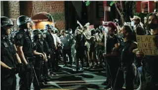  ?? SCOTT HEINS GETTY IMAGES ?? Protesters face off with police officers after violating a curfew in New York City on Thursday night.