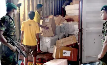  ??  ?? In view of threats from smugglers, Customs officers had to seek help from the Police Special Task Force (STF) yesterday to check a container containing illegally imported items. Pic by M. A. Pushpakuma­ra