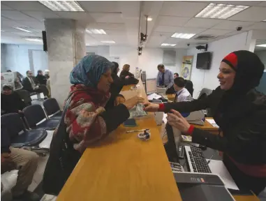  ?? (Mohamad Torokman/Reuters) ?? A WOMAN WITHDRAWS money at the Housing Bank for Trade & Finance in Ramallah on January 22, 2013.