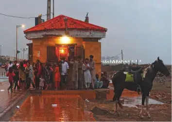  ?? AFP ?? People shelter from the rain next to a roadside building in Karachi. Forecaster­s have predicted widespread rain and thundersto­rms in Karachi, Hyderabad, Thatta, Badin, Dadu and Jamshoro.