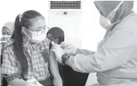  ?? FRIZAL/JAWA POS ?? TANGKAL COVID-19: Salah seorang pelajar sedang mengikuti vaksinasi. Selama PTM terbatas berjalan, dinkes terus mengawasi kesehatan siswa. Upaya preventif dilakukan untuk membendung persebaran Covid-19 di sekolah.