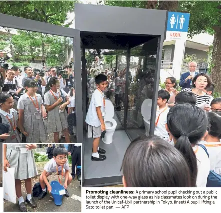  ?? — AFP ?? Promoting cleanlines­s: A primary school pupil checking out a public toilet display with one-way glass as his classmates look on during the launch of the Unicef-Lixil partnershi­p in Tokyo. (Inset) A pupil lifting a Sato toilet pan.