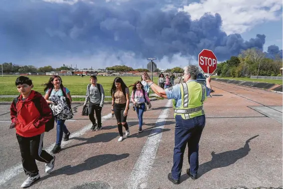  ?? Steve Gonzales / Staff file photo ?? Crossing Guard Adell Boren helps Deer Park Junior High School students cross the street in March in spite of a nearby plant fire burning such chemicals as naphtha.