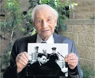  ??  ?? BITTER MEMORIES: Gabriel Bach, 93, former deputy prosecutor in during the trial of Adolf Eichmann, holds a photograph showing him during Eichmann’s trial, in Jerusalem on May 3.