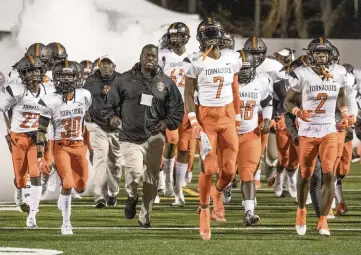  ?? AL DIAZ adiaz@miamiheral­d.com, file 2019 ?? The Booker T. Washington Tornadoes run onto the field before beating Bolles in the Class 4A title game in Daytona Beach on Dec. 11. South Florida schools are concerned the FHSAA’s plan will effectivel­y disqualify them from state-title contention.