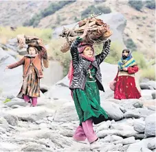  ?? — AFP photo ?? Afghan women carry firewood on their heads in Dara-i Noor district of Nangarhar province. Women in particular have seen hard-won rights evaporate under the Taliban rule, and they are increasing­ly being squeezed out of public life.