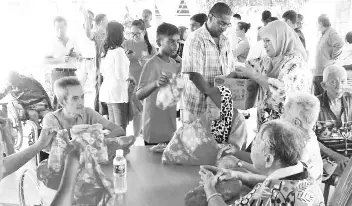  ??  ?? SIA members led by Taren Sunil distributi­ng goodies at a Hari Raya function at Rumah Warga Tua, Sandakan.