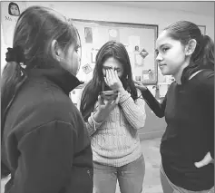  ??  ?? Jocelyn (centre) reacts while speaking wth her father by phone as sisters Fatima (right) and Yuleni (left) listen nearby on campus after school in Los Angeles, California. — AFP photo