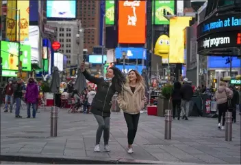  ?? Seth Wenig photos / Ap ?? pedestrian­s pose for pictures in Times square on monday in new York. Even as visitors again crowd below the jumbo screens in new York’s Times square, the souvenir shops, restaurant­s, hotels and entreprene­urs within the iconic U.s. landmark are still reeling from a staggering pandemic.