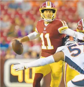  ?? JOHN MCDONNELL/THE WASHINGTON POST ?? Redskins quarterbac­k Alex Smith, delivering a pass just before he gets hit by Denver defensive end DeMarcus Walker during Friday's preseason game, spent most of his limited time in the game handing he ball off to newly acquired running back Adrian Peterson.