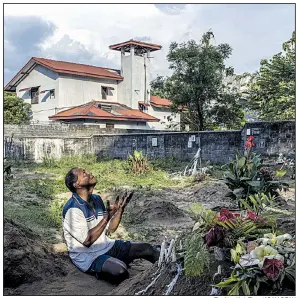  ?? The New York Times/ADAM DEAN ?? Mourner Melton Roy prays Tuesday among the graves for some of Sunday’s bombing victims during burials at Sellakanda Catholic Cemetery in Negombo, Sri Lanka.