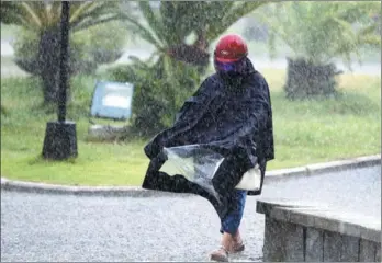  ?? JIANG KEHONG / XINHUA ?? A pedestrian braves heavy rain in Fuqing, Fujian province, on Monday. Tropical Storm Haitang made landfall in the city on Monday morning in the wake of Typhoon Nesat, which roared into the city on Sunday. The government has warned people about the...