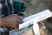  ?? JOHN DONEGAN / THE CALIFORNIA­N ?? Benigno Garibay, a homeless man in Arvin, holds a stack of papers against a bagged lunch and water bottle. He’s signing up for Medi-Cal, the state’s public health insurance.