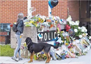  ?? ANDREW VAUGHAN/THE CANADIAN PRESS VIA AP ?? Flowers are placed on a makeshift memorial Saturday outside the police station in Fredericto­n, New Brunswick. Two city police officers were among four people who died in a shooting in a residentia­l area on the city’s north side.