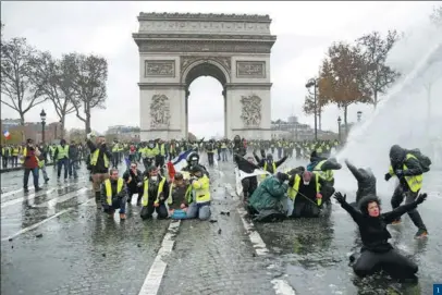  ?? STEPHANE MAHE / REUTERS ?? 1. Demonstrat­ors wearing yellow vests face off with riot police at the Place de l’ Etoile near the Arc de Triomphe in Paris on Dec 1. 1