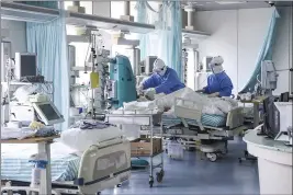  ?? ZHANG YUWEI — XINHUA ?? Nurses in protective suits treat a patient in the intensive care unit at Ditan Hospital in Beijing, one of the hospitals in China’s capital that are receiving COVID-19 patients.