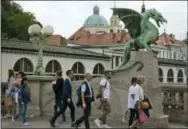  ?? DARKO BANDIC — THE ASSOCIATED PRESS FILE ?? FILE- In this photo, tourists and residents walk by a statue of a dragon, a symbol of the city, in downtown Ljubljana, Slovenia. The tiny European nation of Slovenia is getting an outsize share of attention lately. Not only has Melania Trump, wife of...
