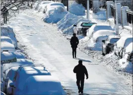  ?? Michael Dwyer ?? The Associated Press People walk past rows of snow-covered cars Wednesday on Marginal Street in Boston. The Boston area was hit with its third nor’easter of the month on Tuesday.