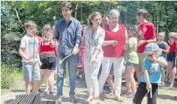  ??  ?? Hadrien Trudeau, right, reacts to campfire smoke Friday as his brother Xavier, left, father Justin and mother Sophie Grégoire Trudeau roast marshmallo­ws Friday at a day camp in Shelburne, N.S.