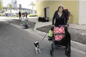  ?? ALIE SKOWRONSKI askowronsk­i@miamiheral­d.com ?? Eli, a veteran, walks with her dog on Thursday after she and her partner packed up all of their belongings when city of Miami police told them to vacate the area by the Miami River in downtown Miami.