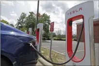  ??  ?? A Tesla vehicle charges at a Tesla Supercharg­er site in Charlotte, N.C. [AP PHOTO]