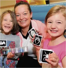  ??  ?? Tattoos Lynn Coull provides glitter tattoos for four year olds Rose Murdoch, left, and Amelia Humphries