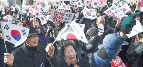  ?? — AFP ?? Supporters of South Korean President Park Geun-Hye wave the national flags during a rally against the impeachmen­t of the president outside the ruling Saenuri Party in Seoul on Tuesday.