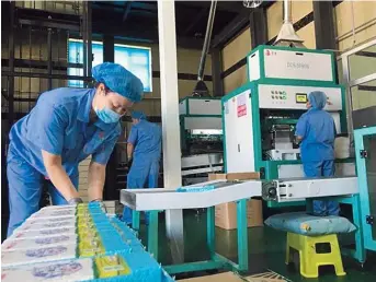  ??  ?? Nianyugou workers pack rice in one of the group’s plants.