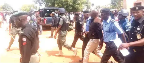  ??  ?? Armed security men protecting Kaduna House of Assembly member, Mark Yari after rescuing him from a mob attack during re-run council elections in the state