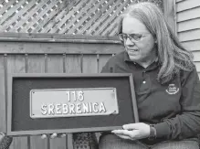  ?? ANDREW WATERMAN THE TELEGRAM ?? Lesleyanne Ryan on her back deck in Mount Pearl, holding a licence plate given to her by a teenage boy in Srebrenica.