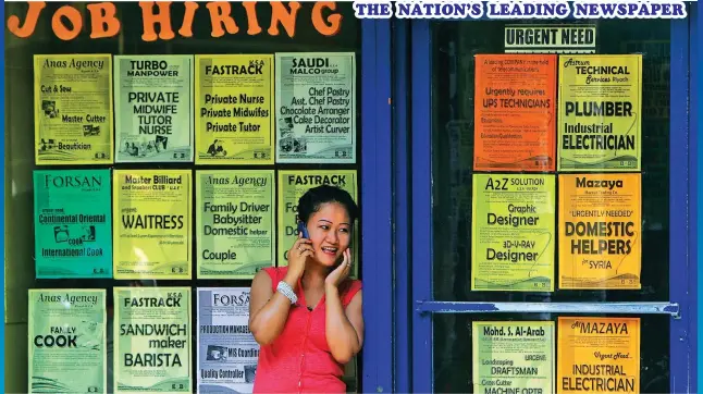  ??  ?? A Filipino talks on her mobile phone outside an office offering overseas job opportunit­ies in foreign countries. The reason for the dream to work abroad is obvious — the financial compensati­on is more than what one can get from a similar job in the Philippine­s. (EFE/EPA Rolex dela Peña)