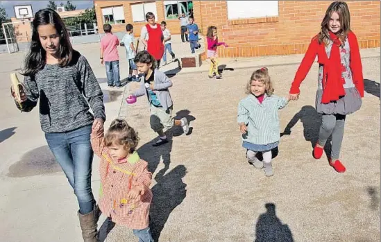  ?? VICENÇ LLURBA ?? Clara y Martina, las dos con bata, cuidadas por alumnas mayores en el patio de la escuela de Godall, ante la mirada de su educadora