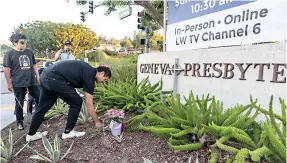  ?? AP Photo/Damian Dovarganes ?? ■ Hector Gomez, left, and Jordi Poblete, worship leaders at the Mariners Church Irvine, leave flowers outside the Geneva Presbyteri­an Church on Sunday in Laguna Woods, Calif., after a fatal shooting.