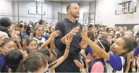  ?? JEFF CHIU/AP ?? The Golden State Warriors’ Stephen Curry, center, greets basketball camp participan­ts in Walnut Creek, Calif., in August. His shoes are now marketed to all kids, not just boys.