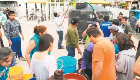  ??  ?? Contenedor­es con agua fueron colocados en la vía pública para que los residentes se abastezcan durante la contingenc­ia.