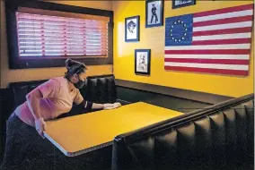  ?? [CHRIS LANDSBERGE­R/ THE OKLAHOMAN] ?? Rib Crib shift manager Kelsey Parker wipes down tables and seating areas to prepare the restaurant in Yukon for its reopening at 11 a.m. Friday.