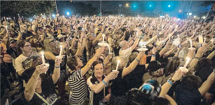  ?? BRANDON DILL / AP ?? Miles de fans sostienen velas encendidas durante la vigilia por el aniversari­o de la muerte de Elvis Presley frente a Graceland, su mansión en Memphis