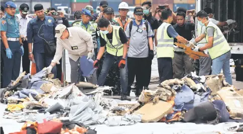  ??  ?? Rescue workers load up recovered debris onto a truck at Tanjung Priok port.