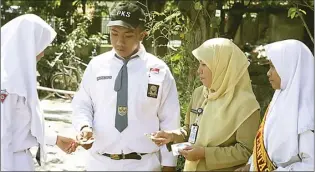  ??  ?? BERJALAN LIMA TAHUN: Fety Susilawati­e bersama anggota komunitas Pelopor Keselamata­n Berlalu Lintas (PKB) di SMAN 1 Gedangan.