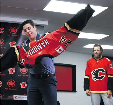  ?? GAVIN YOUNG ?? Defenceman Travis Hamonic tries on his new jersey under the watchful eyes of goaltender Mike Smith after being introduced by the Flames to the media Monday at the Scotiabank Saddledome.