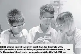  ?? PBSP ?? PhOTO shows a student-volunteer (right) from the University of the Philippine­s in los Baños, while helping schoolchil­dren from Ricardo P. Cruz Sr. elementary School conduct an experiment at the Kids’ lab 2019.