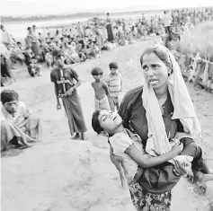  ??  ?? A Rohingya refugee woman who crossed the border from Myanmar a day before, carries her daughter and searches for help as they wait to receive permission from the Bangladesh­i army to continue their way to the refugee camps, in Palang Khali, Bangladesh. — Reuters photo