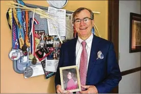  ?? PHIL MASTURZO / BEACON JOURNAL ?? Dr. Al Ciraldo holds a photo of his late wife, Debbie, who died of breast cancer 17 years ago. Ciraldo stands with racing medals from his years participat­ing in the Susan B. Komen Race for the Cure. This year’s race will be his 22nd.