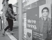  ?? [STEVEN SENNE/ASSOCIATED PRESS FILE PHOTO] ?? A passerby walks past an employment hiring sign while entering a Target store location in Westwood, Mass.
