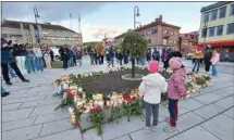  ?? PAL NORDSETH / AP ?? People gather around flowers and candles Thursday after a man killed several people in Kongsberg, Norway, Wednesday.