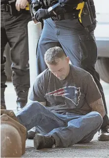  ?? STAFF PHOTO BY MARK GARFINKEL ?? UNDER ARREST: A man detained by Massachuse­tts state police and Revere police officers is seen after his apprehensi­on in a parking lot near the TD Garden, following a car chase from a bank robbery in Revere.