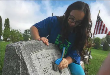  ?? ZACH SRNIS — THE MORNING JOURNAL ?? Kate Bartlow, 15, an eighth-grade South Amherst Middle School student, brushes off the tombstone of Dustin Michael Slack.