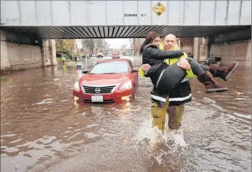  ?? Genaro Molina
Los Angeles Times ?? YASMIN FERNANDEZ, 28, is carried by L.A. firefighte­r Jose Rodriguez after her car stalls in a flooded section of Avenue 26 in Lincoln Heights during the start of a series of El Niño-generated storms this week.